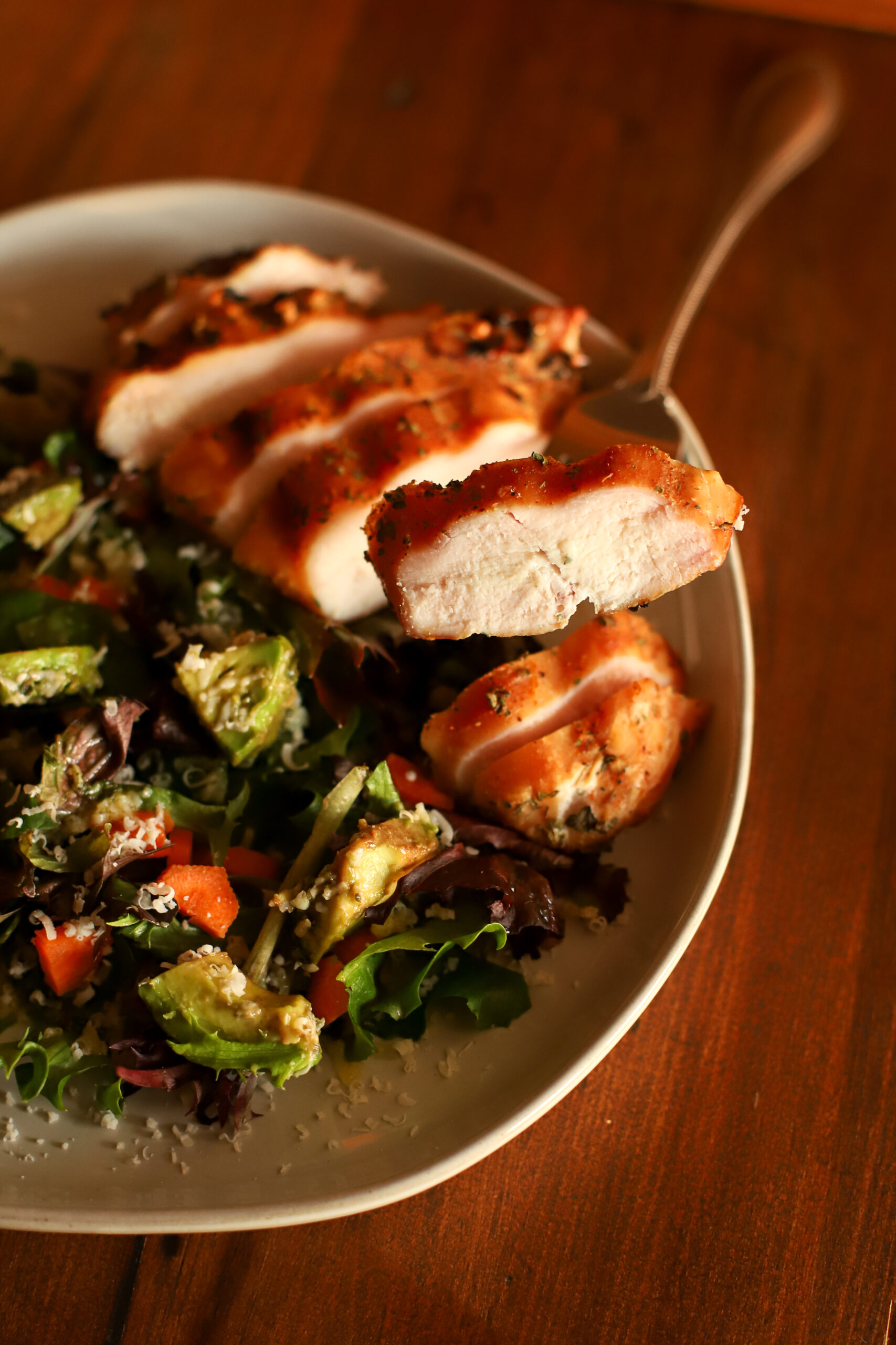 close up image of sliced smoked chicken on a plate with salad