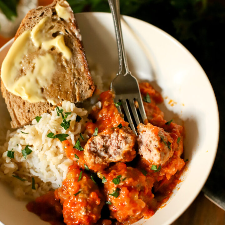 up close shot of italian pork meatballs in a bowl with rice and bread