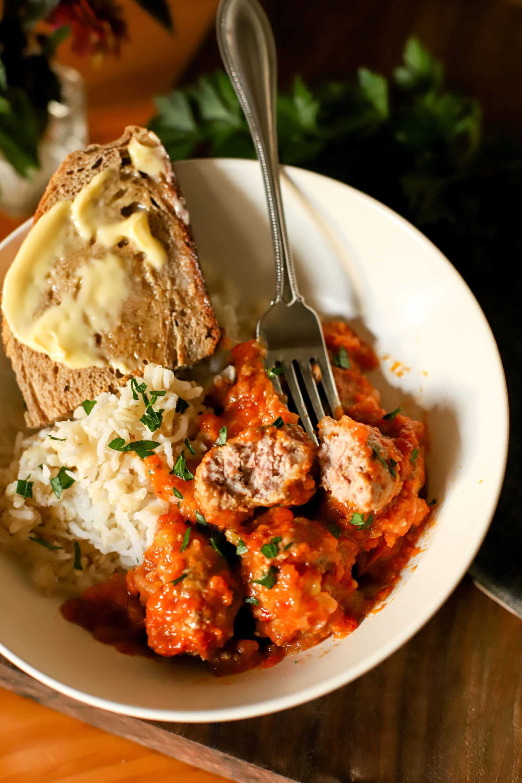 up close shot of italian pork meatballs in a bowl with rice and bread