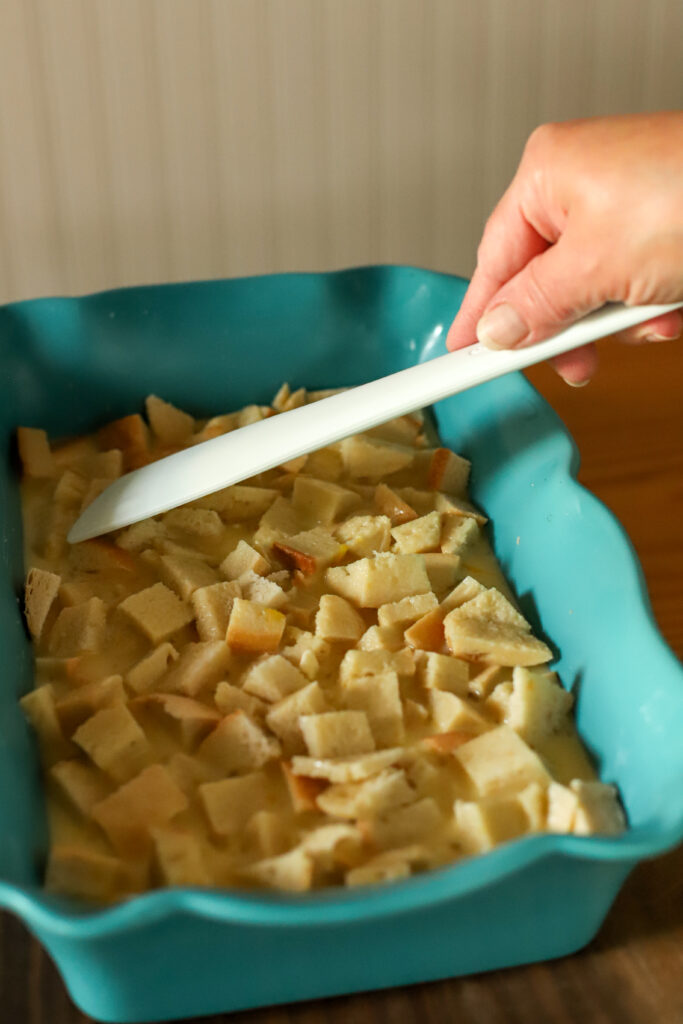 pressing down egg and milk mixture  into cubed bread