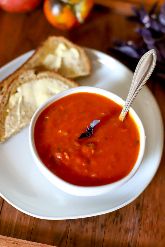 bowl of tomato soup served with buttered bread