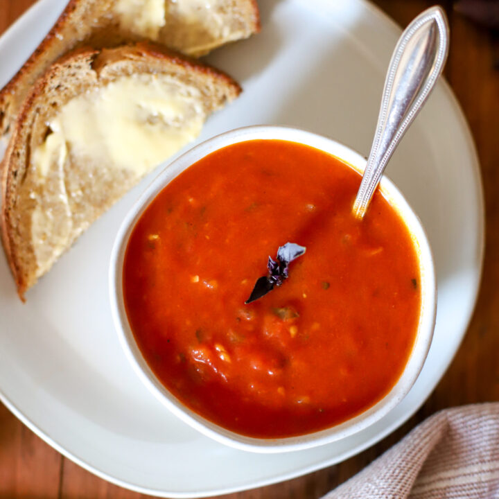 bowl of tomato soup being served with buttered bread