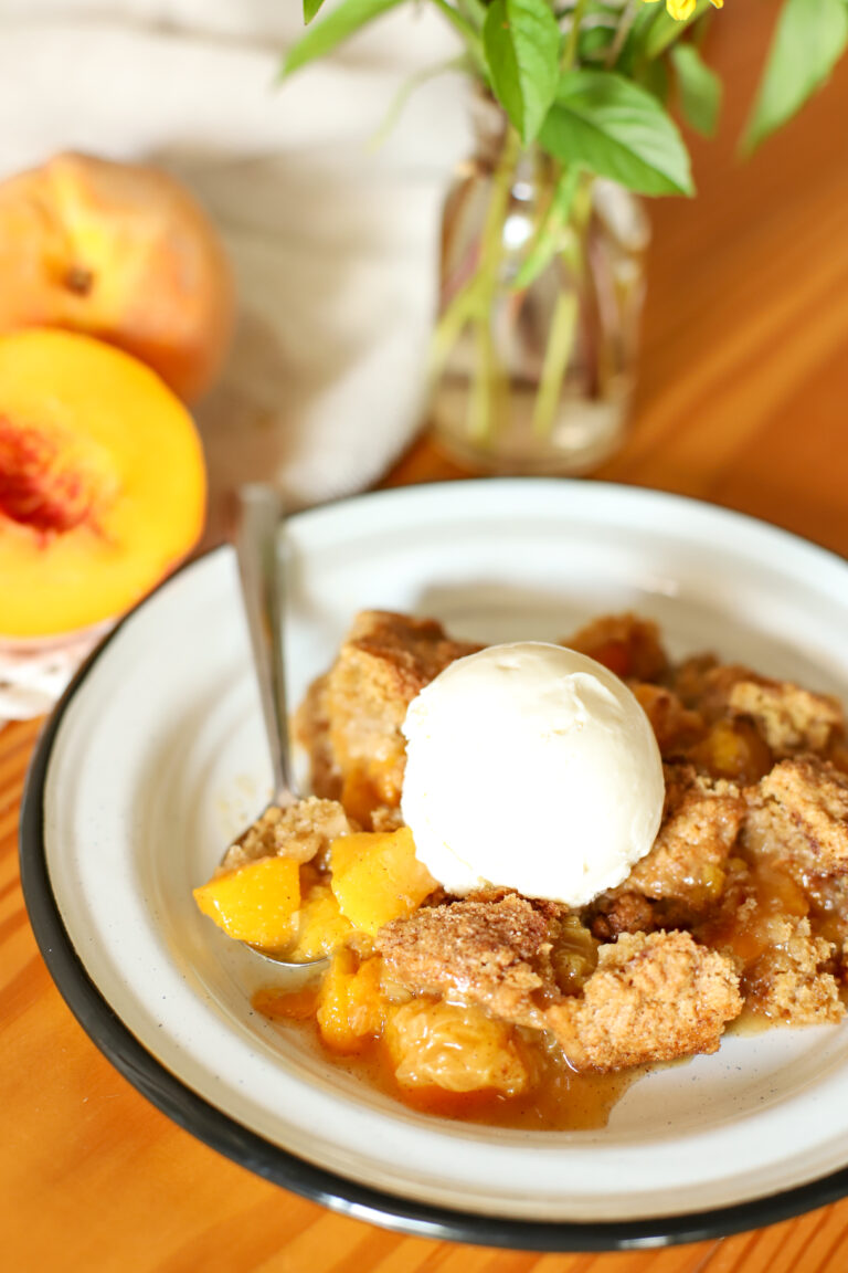 bowl of freshly milled peach cobbler topped with vanilla ice cream
