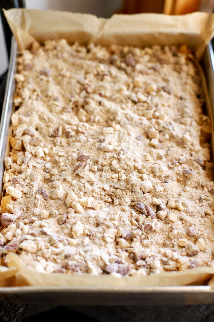 up close shot of streusel topping mixture sprinkled over top of freshly milled apple pie bars