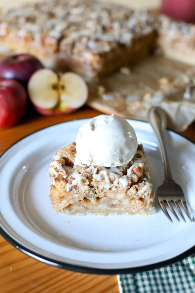 up close shot of apple pie bar on a plate with a scoop of ice cream
