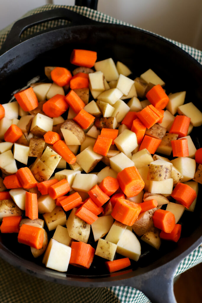 diced carrots, potatoes, and onions in a cast iron skillet