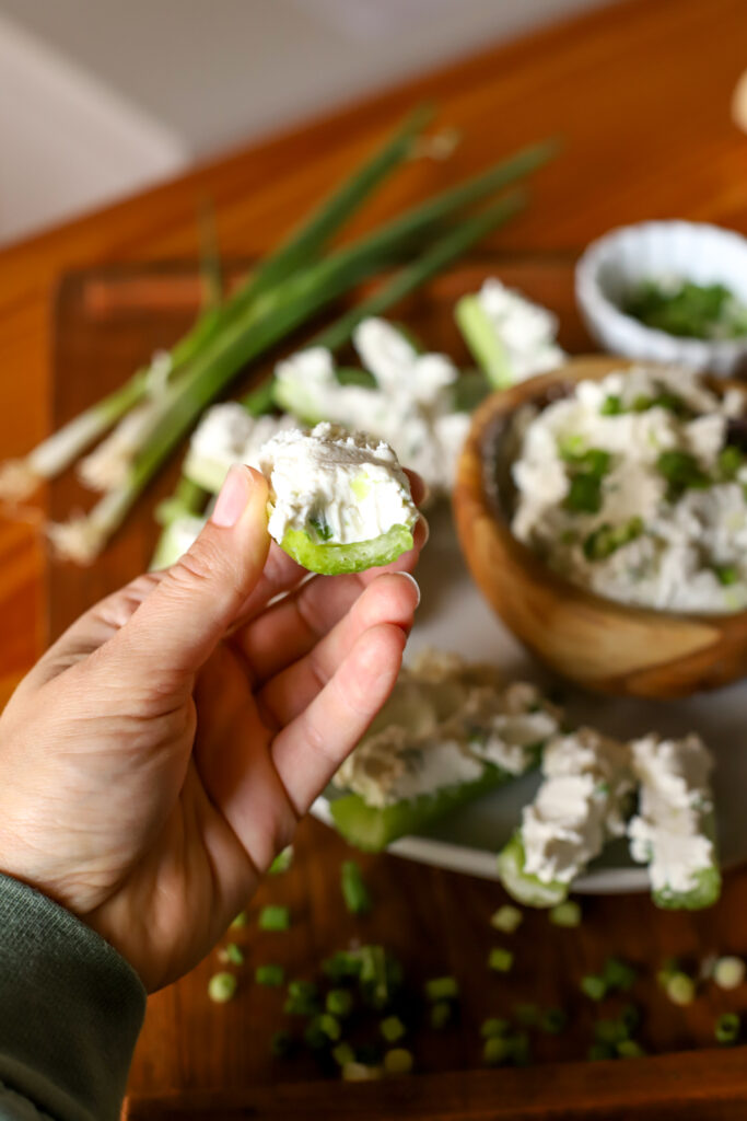 hand holding cream cheese stuffed celery