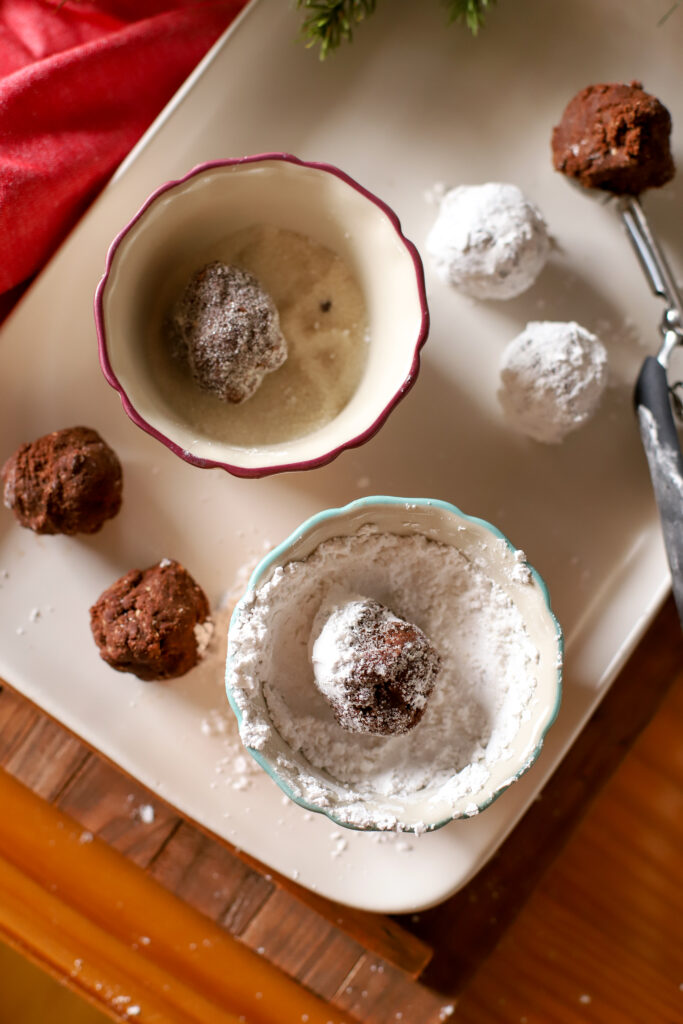 rolling crinkle cookie balls in white sugar and powdered sugar