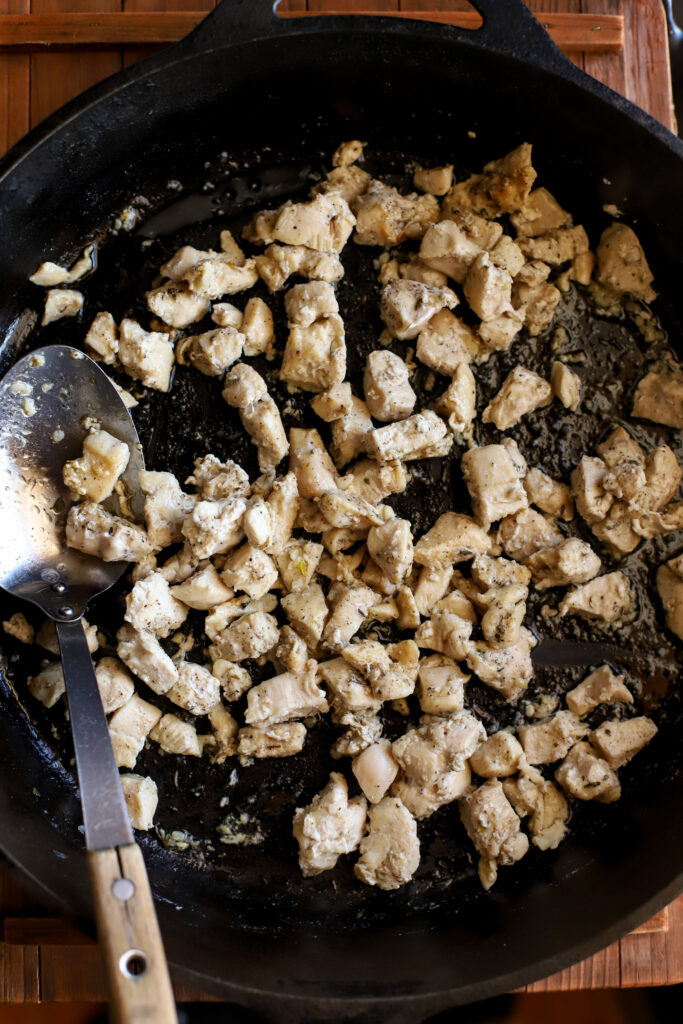 up close shot of chicken sautéing in a cast iron skillet