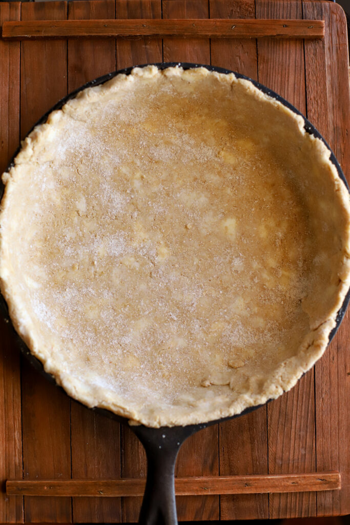 up close shot of rolled out fresh milled pie crust in a cast iron skillet