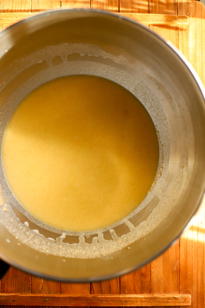 up close shot of wet ingredients in a bowl for sourdough dinner rolls