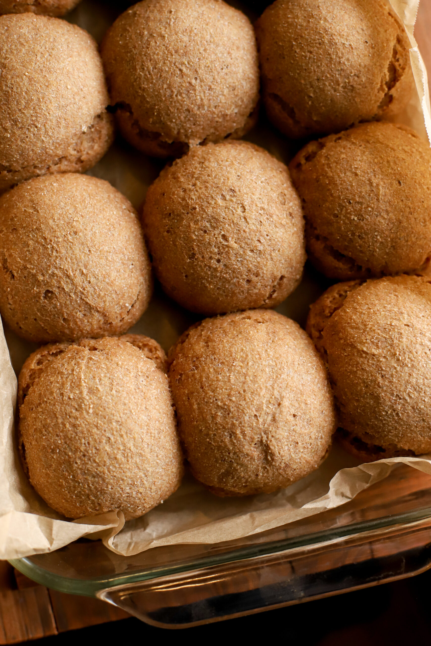 up close shot of baked soft fresh milled sourdough dinner rolls in a baking pan