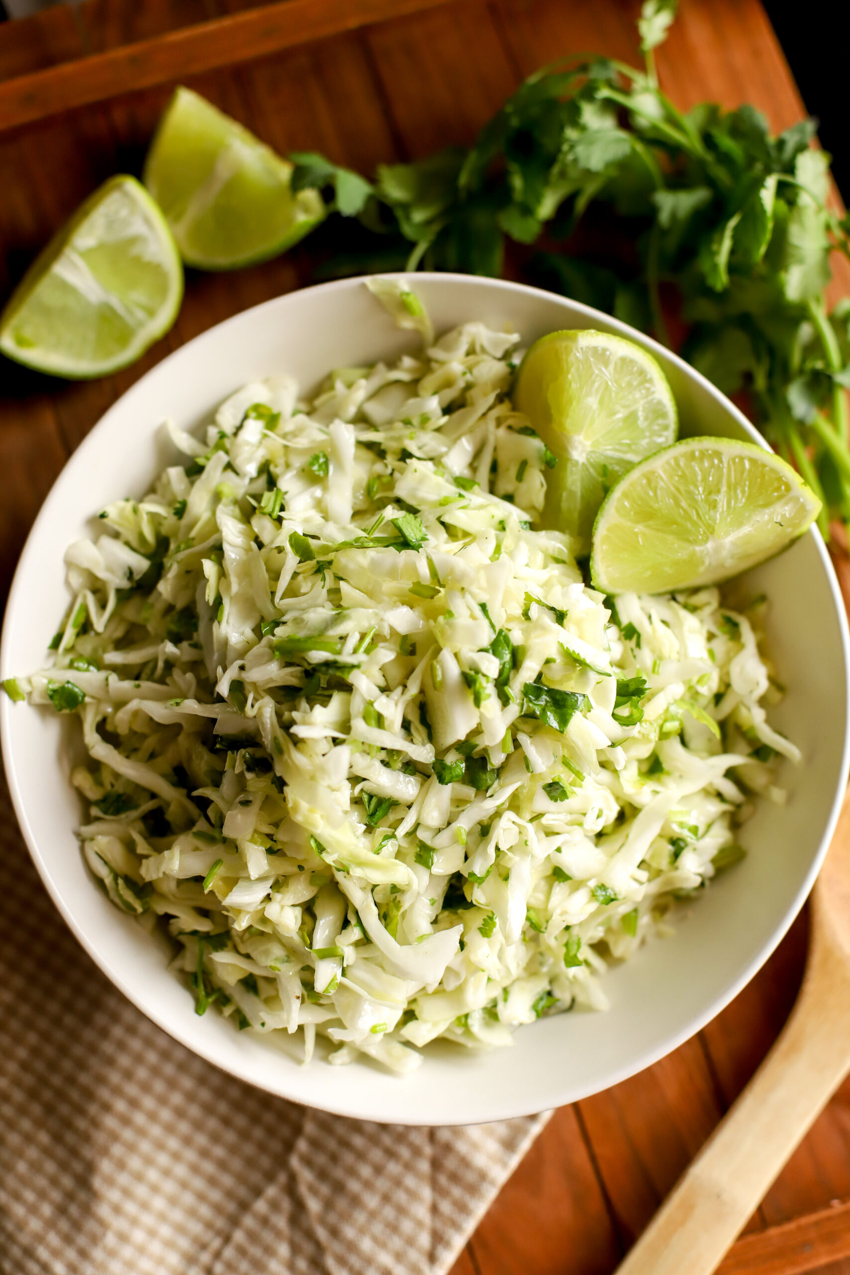 up close shot of Cilantro Lime Cabbage Slaw in a bowl with slice limes as garnish