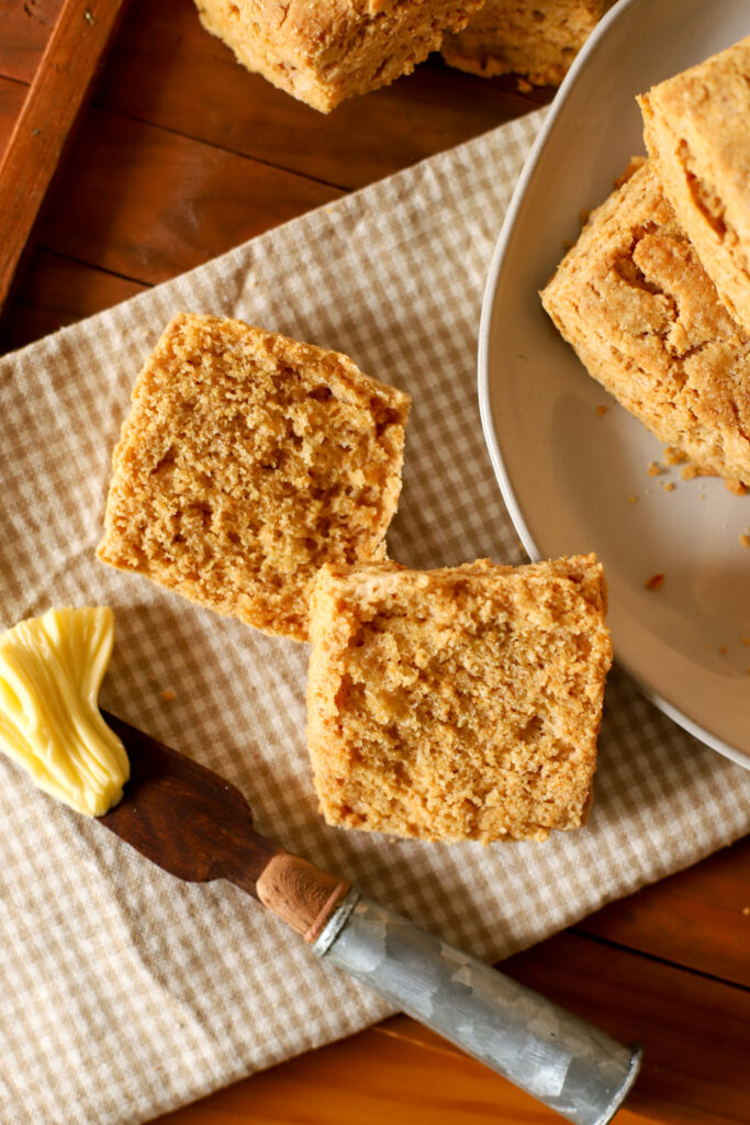 up close shot of fresh milled biscuit cut in half on a table with other biscuits on a plate beside it