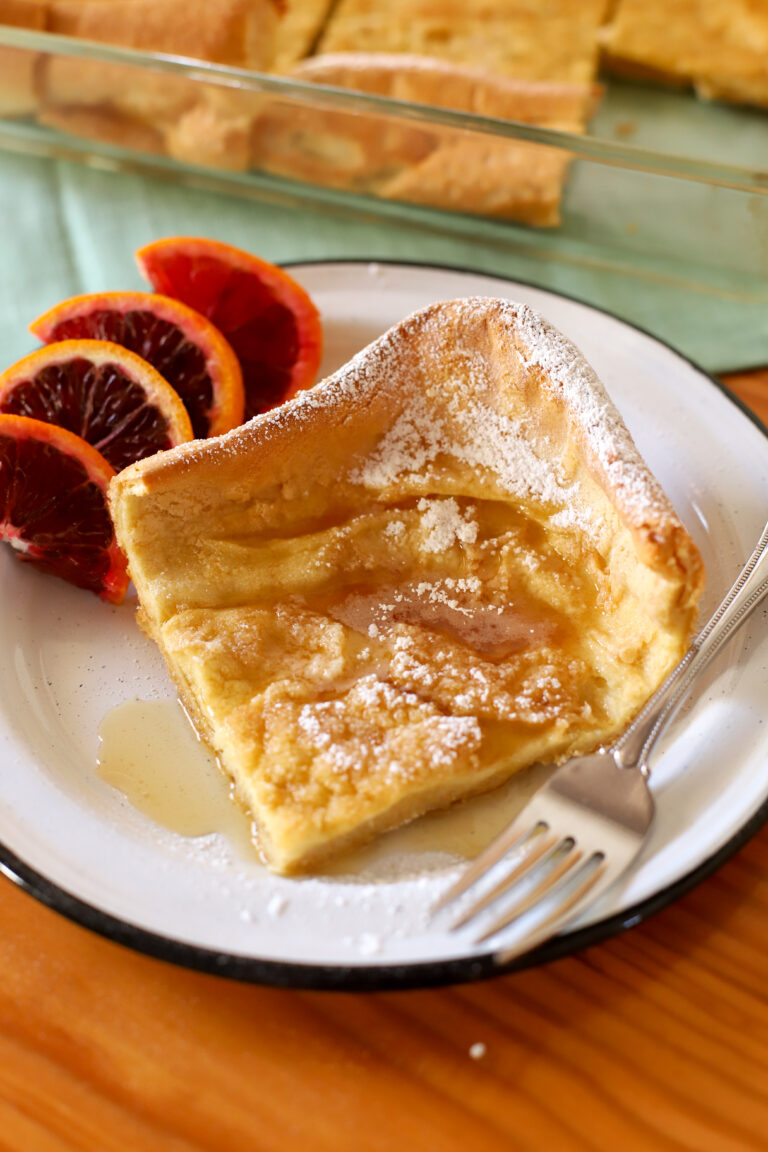 up close shot of slice of fresh milled german pancakes on a plate with slices oranges