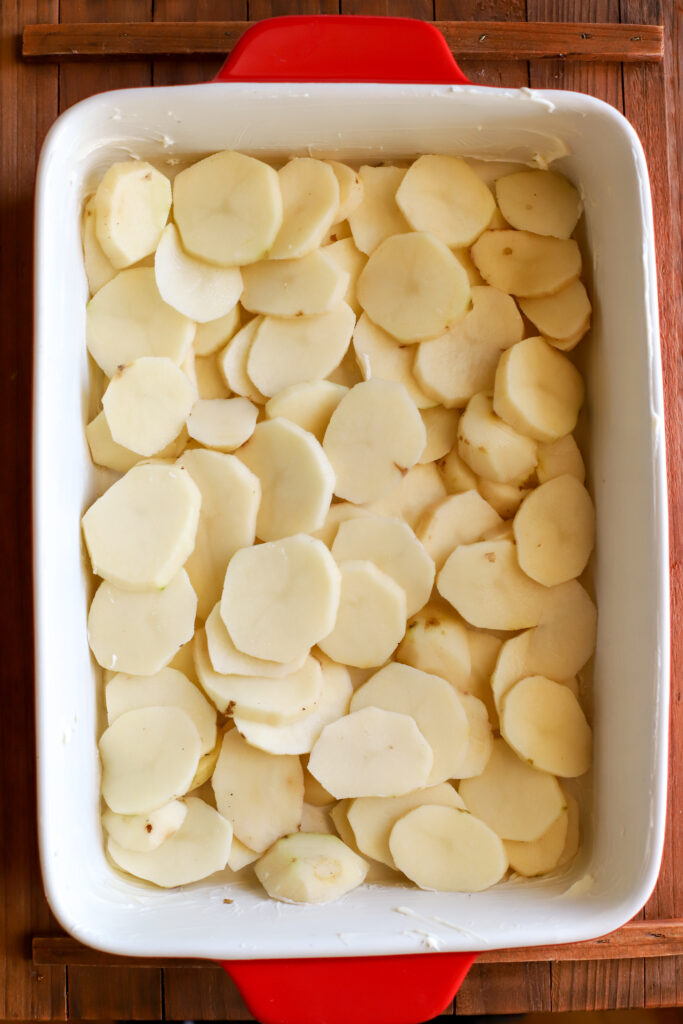 up close shot of thinly sliced potatoes layered in a 9x13 baking dish