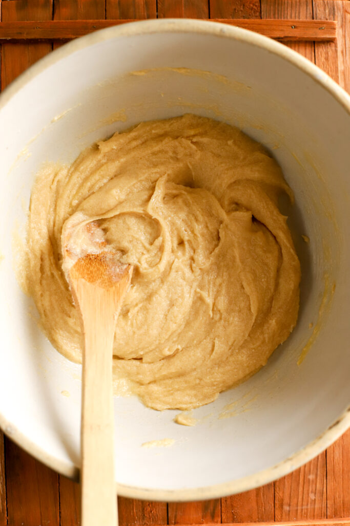 up close shot of a bowl of butter, eggs, and sugar creamed together with a wooden spoon