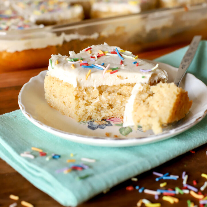 up close shot of a slice fresh milled vanilla cake with a bite taken out on a plate with sprinkles scattered over it