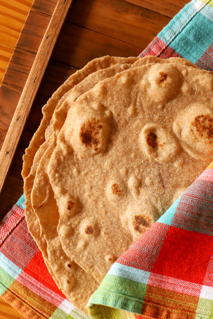 up close shot of quick no yeast fresh milled tortillas wrapped in a colorful checkered towel