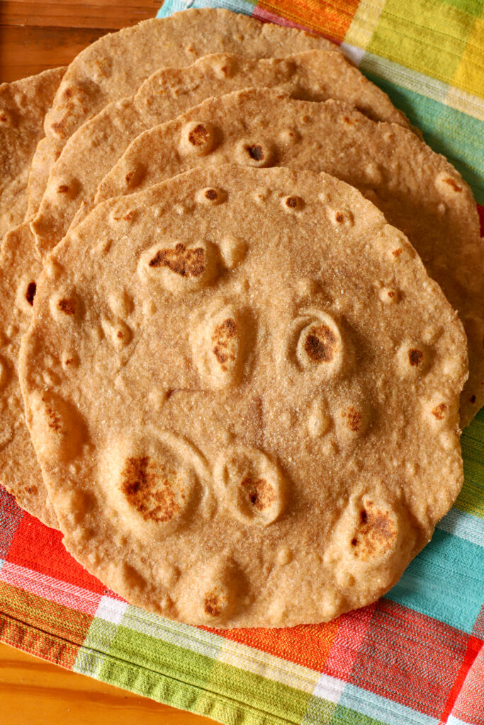 up close shot of quick no yeast fresh milled tortilla stacked on a checkered towel