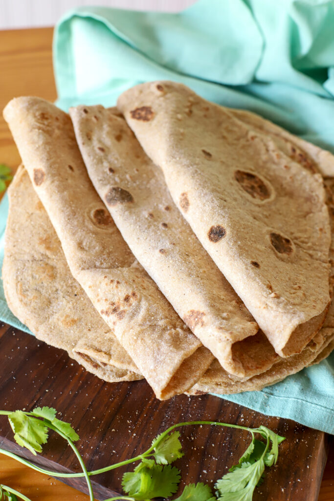 up close shot of fresh milled sourdough tortillas folded next to eachother on a blue towel