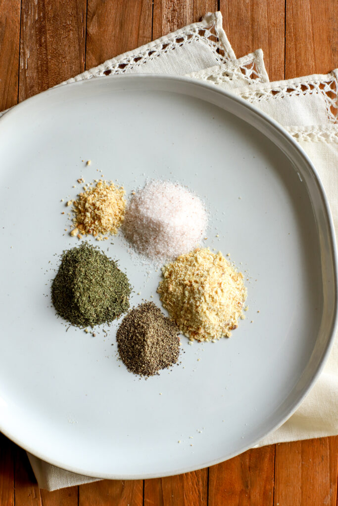 up close shot of a plate with black pepper, onion powder, garlic powder, dried dill and salt for homemade ranch dressing