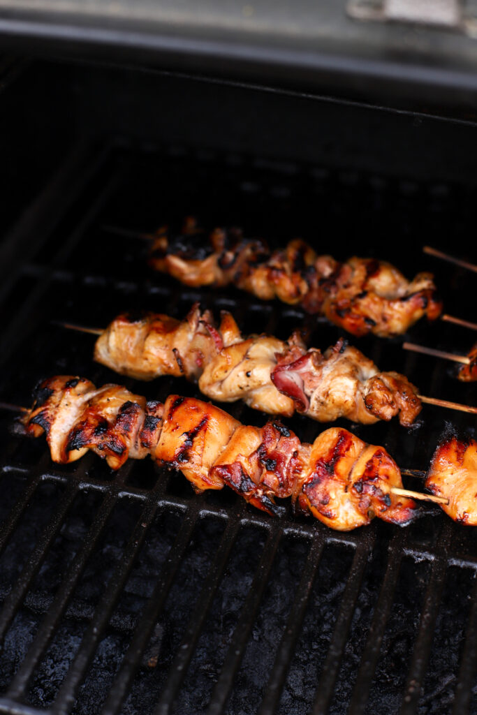 up close shot of chicken and bacon on a skewer in a smoker