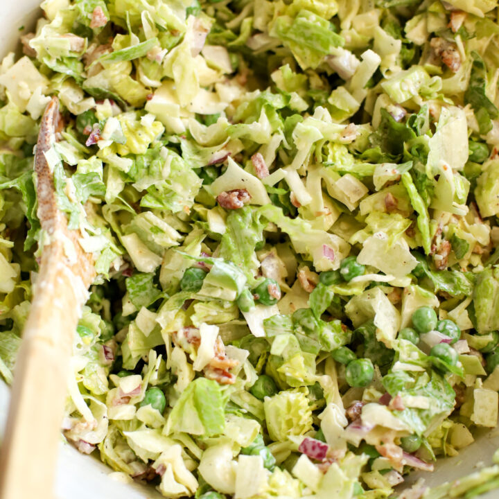 up close shot of simple chopped 7 layer salad in a stoneware bowl with a wooden spoon sitting on a teal blue towel
