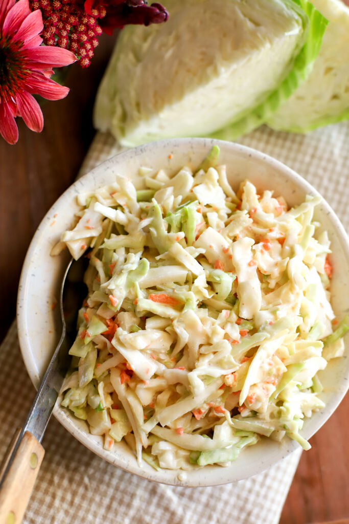 up close shot of cabbage coleslaw in a bowl with a spoon
