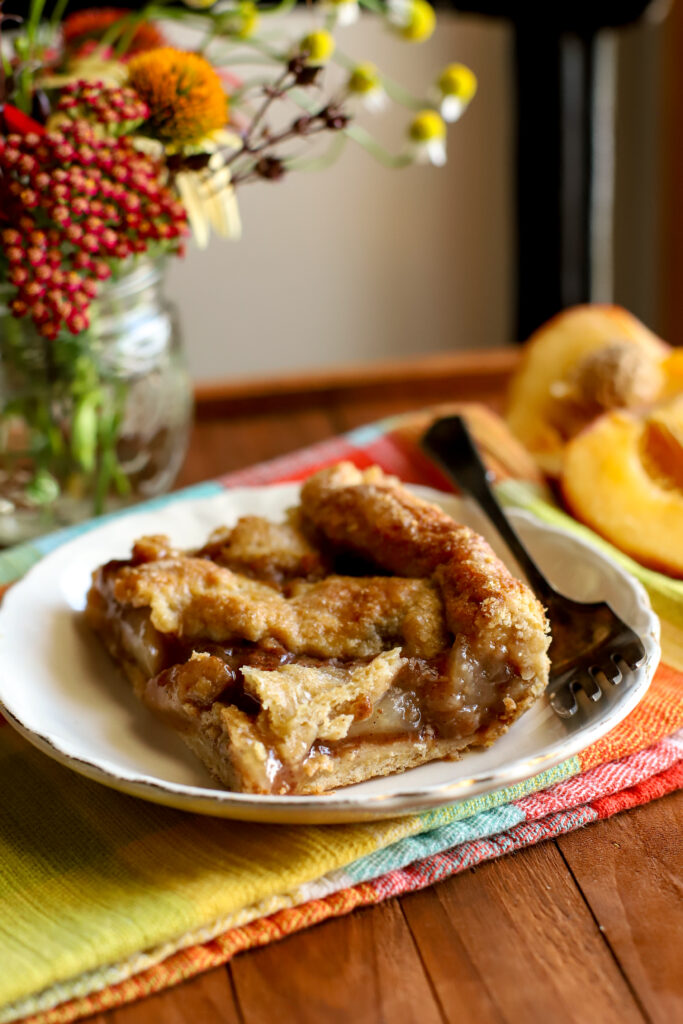 an up close shot of a slice of fresh milled peach pie bars on a plate
