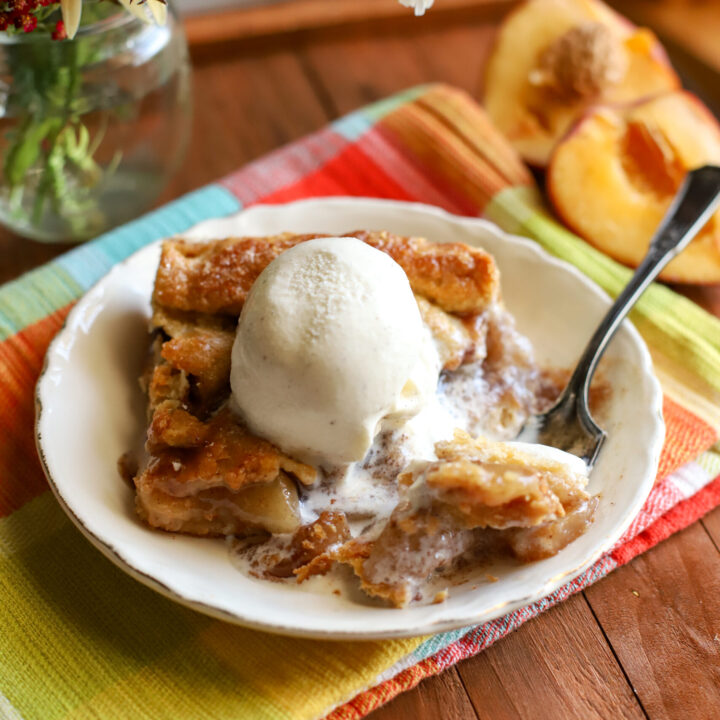 up close shot of slice of peach pie bars with a scoop of melting vanilla ice cream on top