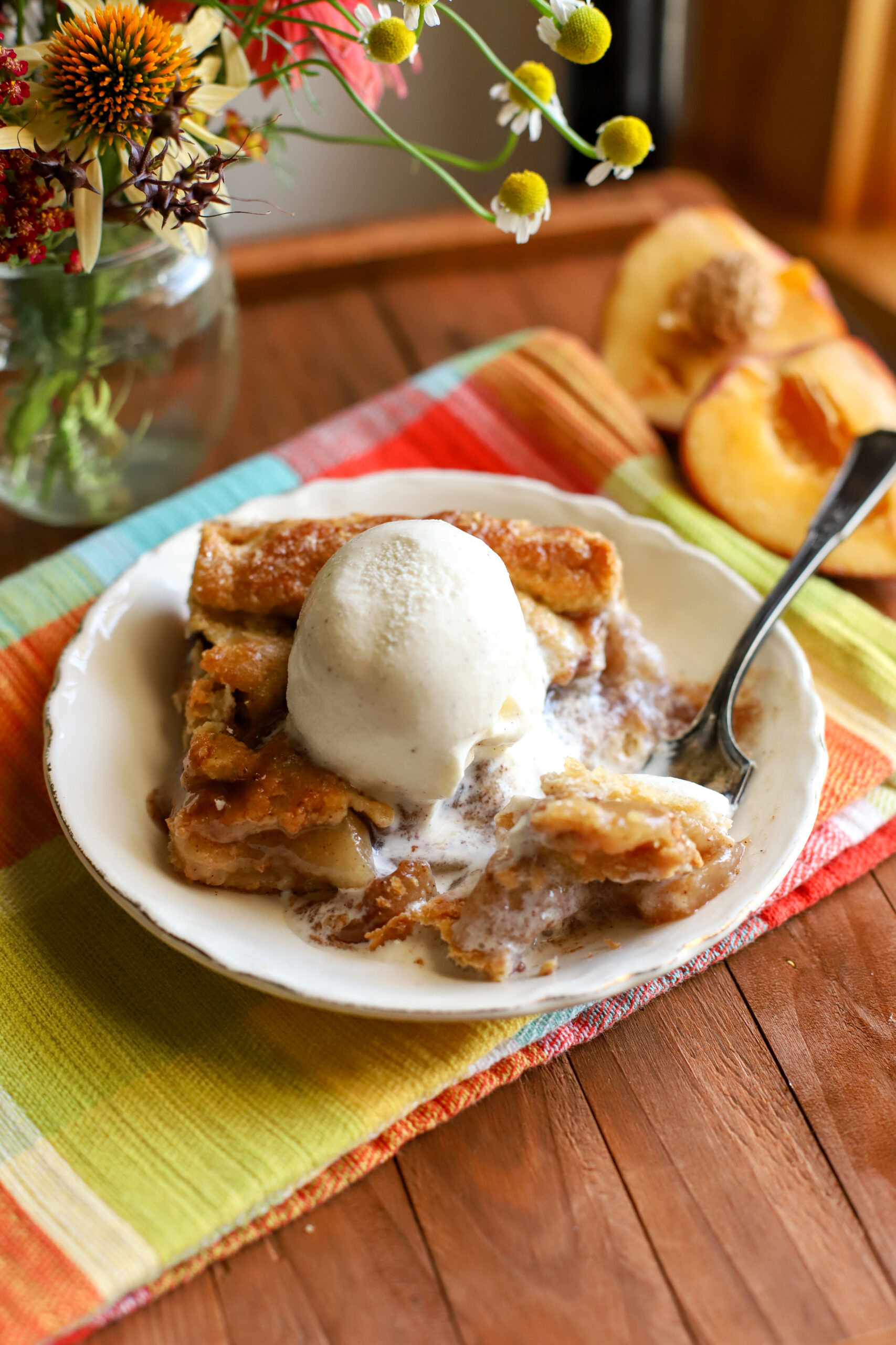 up close shot of slice of peach pie bars with a scoop of melting vanilla ice cream on top
