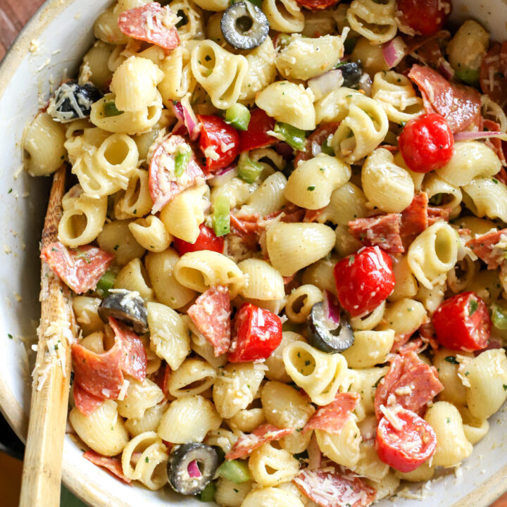 up close shot of a stoneware bowl filled with Easy Pasta Salad With Homemade Italian Dressing on a wood table