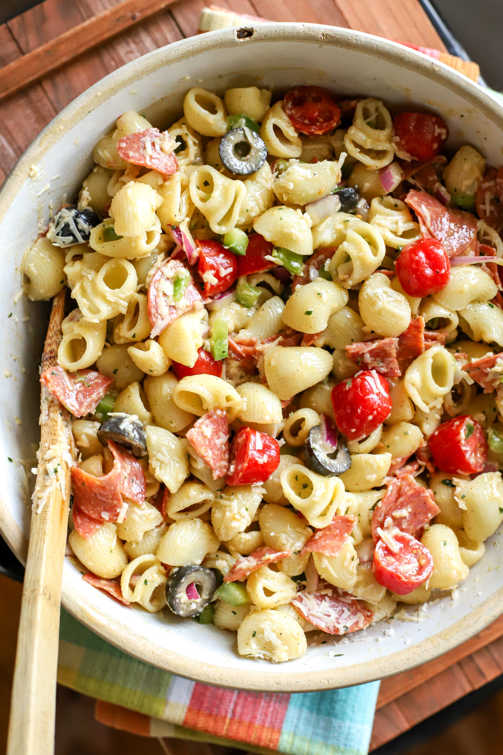 up close shot of a stoneware bowl filled with Easy Pasta Salad With Homemade Italian Dressing on a wood table