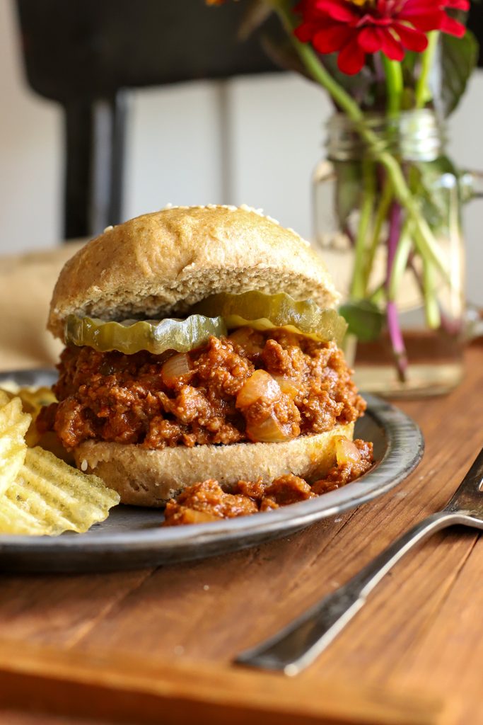 up close shop of easy sloppy joe recipe on a fresh milled sourdough bun with pickles